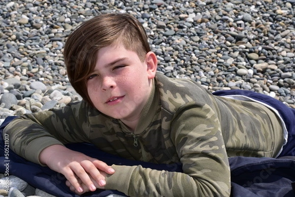 Obraz Boy lying on a pebble beach close-up