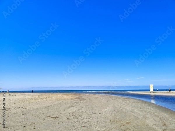 Fototapeta The Black Sea in spring with waves and sand on the beach with a bright blue sky.