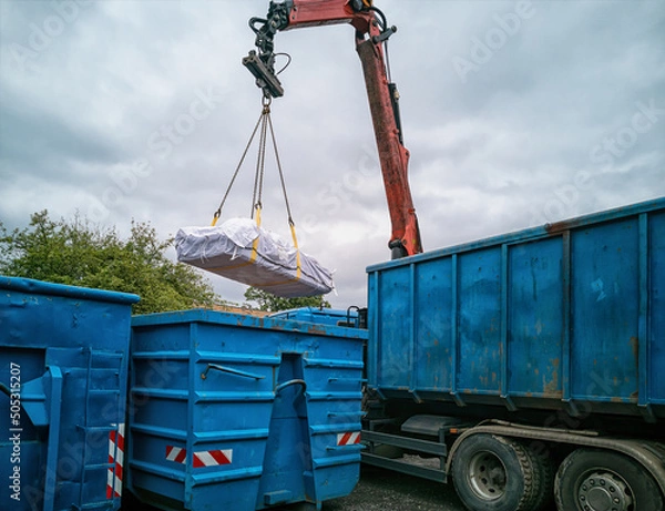 Obraz Crane truck with asbestos bag being reloaded into another container at a recycling yard.