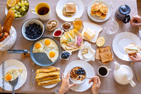 Obraz Breakfast on the table top view.Food on the table top view.Muesli with berries. Fried eggs. Meal day. Buffet. Delicious breakfast. Croissants for breakfast. Lots of food top view. Oatmeal. Muesli with