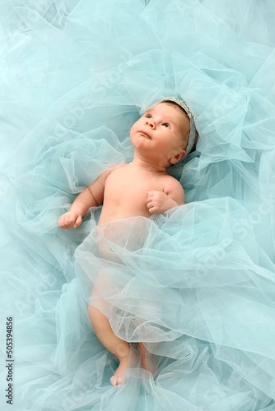 Obraz Infant baby princes with crown lye in cloud of pastel blue background and look up