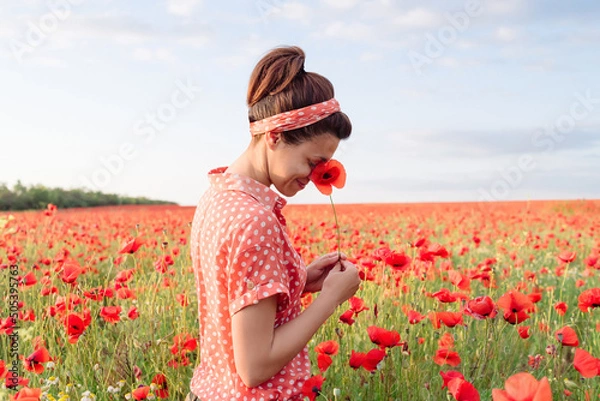 Obraz Happy smiling woman hide her smiling face in Poppy flower among red meadow.