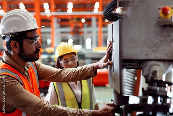 Obraz Two maintenance engineers men and women inspect relay protection system with control machinery. They work a heavy industry manufacturing factory.