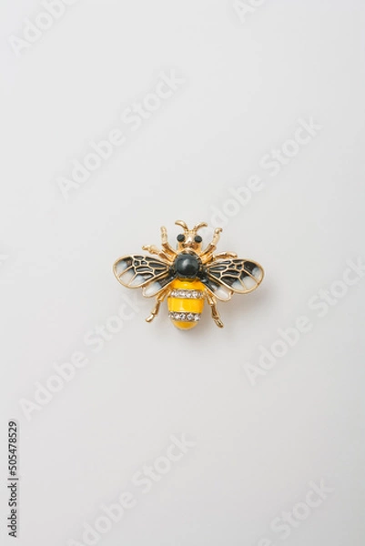 Fototapeta Metallic brooch in shape of bee with gemstones imitation, pin on white background, bijouterie, jewelry close up