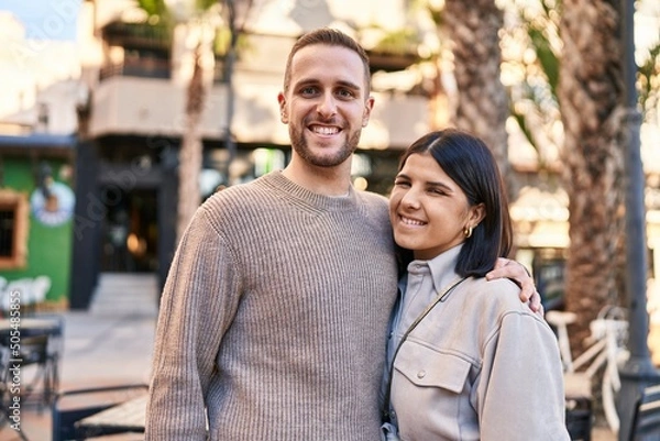 Fototapeta Man and woman couple smiling confident hugging each other standing at street