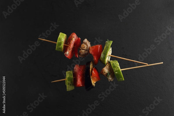 Obraz bbq concept - bbq vegetables on wooden skewers on black background flat lay