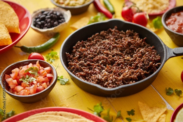 Fototapeta Various fresh and tasty ingredients for chilli con carne. With meat on iron pan