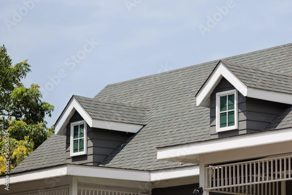 Fototapeta Roof shingles with garret house on top of the house. dark asphalt tiles on the roof background on afternoon time. dark asphalt tiles on the roof background