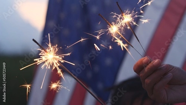 Obraz Happy 4th of July Independence Day, Hand holding Sparkler fireworks USA celebration with American flag background. Concept of Fourth of July, Independence Day, Fireworks, Sparkler, Memorial, Veterans