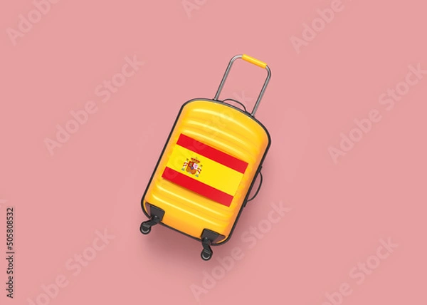 Fototapeta Orange color travel luggage and Spanish flag. On pink coral color background. Horizontal composition. The background is an endless backdrop. Isolated with clipping path.