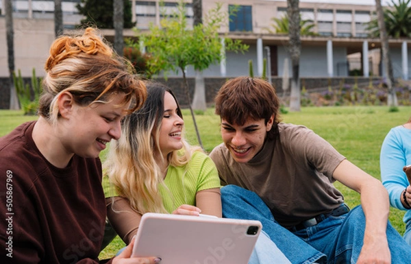 Obraz Group of college students using tablets on campus grass