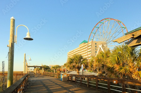 Fototapeta Iconic Carolina Beach Boardwalk at sunrise, Carolina Beach North Carolina USA. Boardwalk hugging a sandy beach with kid-friendly rides and snack bars, plus concerts and fireworks.