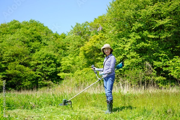 Fototapeta 草刈り機で草刈りをする中年女性　カメラ目線