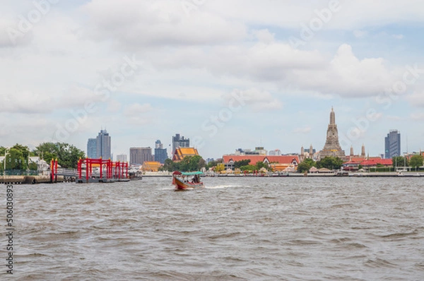 Fototapeta A longtail boat, the Chao Phraya River, the Thai royal first class Temple Wat Arun and the Cityscape of Bangkok Thailand Southeast Asia
