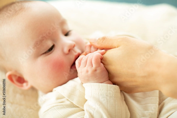 Fototapeta 母親の指を握る赤ちゃん