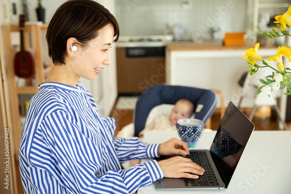 Fototapeta 赤ちゃんをあやしながら仕事をする母親