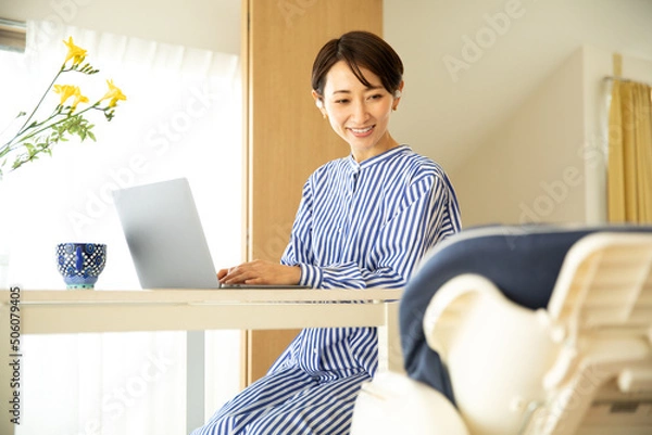 Obraz 赤ちゃんをあやしながら仕事をする母親