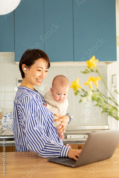 Obraz 赤ちゃんをあやしながら仕事をする母親