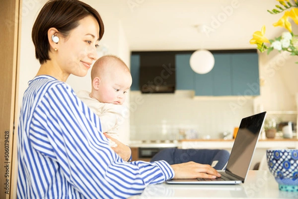 Obraz 赤ちゃんをあやしながら仕事をする母親