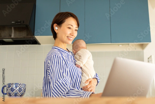 Obraz 赤ちゃんをあやしながら仕事をする母親