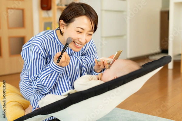 Obraz 化粧をしながら赤ちゃんをあやす母親
