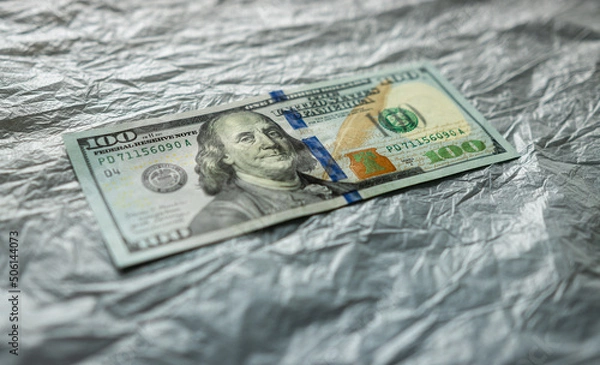 Fototapeta textured background of one hundred dollar bill with a portrait of us President Franklin in orange, red and black colors. blur, defocus.