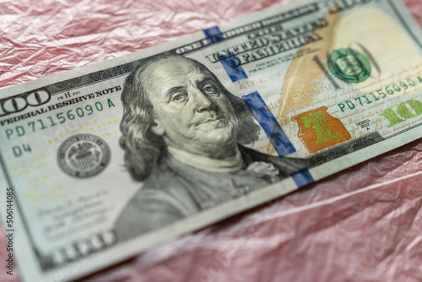Fototapeta textured background of one hundred dollar bill with a portrait of us President Franklin in orange, red and black colors. blur, defocus.