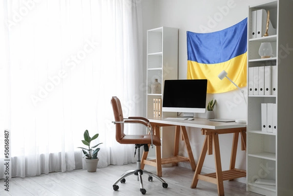 Fototapeta Interior of modern office with workplace, shelving units and hanging Ukrainian flag