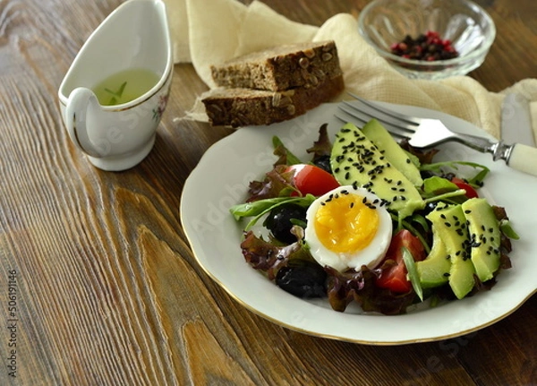 Obraz Avocado salad with olives, tomatoes, lettuce, arugula and boiled egg, copy space