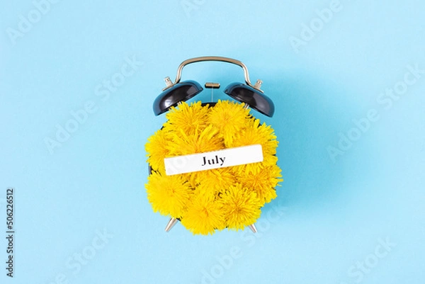 Obraz Calendar summer month July and alarm clock with yellow dandelions flowers on face, blue background. Top view Flat lay. Creative minimal concept July time. Top view, Flat lay, greeting card