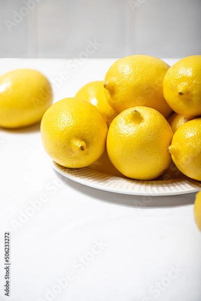 Obraz Plate with fresh lemons in a ceramic plate on the table covered with a linen tablecloth. Copy space