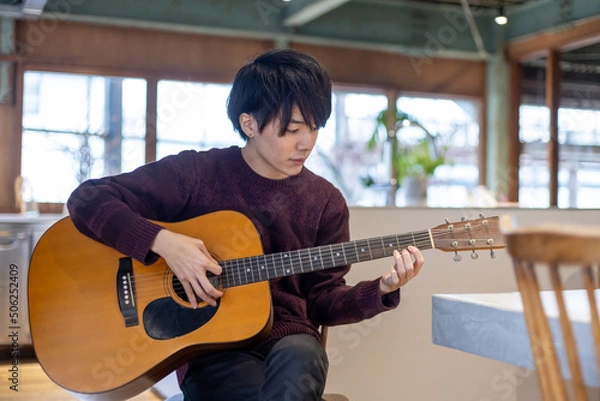 Fototapeta ギター演奏の練習をする20代男性