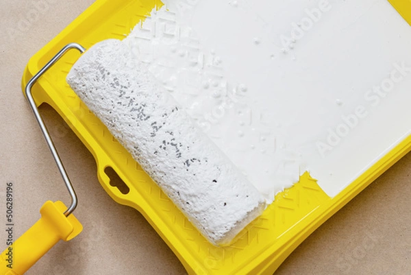 Obraz Painting apartment, renovating with white color paint. Paint roller in paint tray with white color in the tray on brown paper