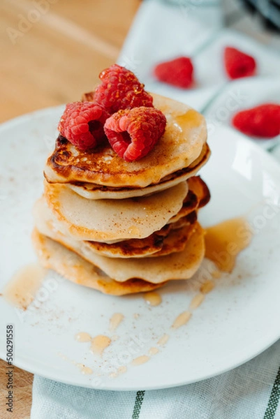 Fototapeta Pancakes with raspberries lying on the table, stacking