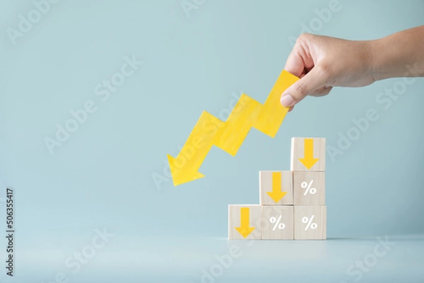 Fototapeta Yellow paper cut arrow going down negative trend on wooden blocks with percentages. Concept of profit decreasing in percentage.