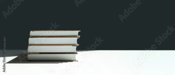 Fototapeta a stack of books on a white table. books with shadow from the sun.