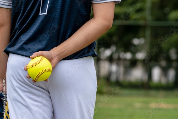 Obraz A young Softball player ready to peatch from his position in the outfield.holding a Softball ball in his hands while playing catch in the outfield