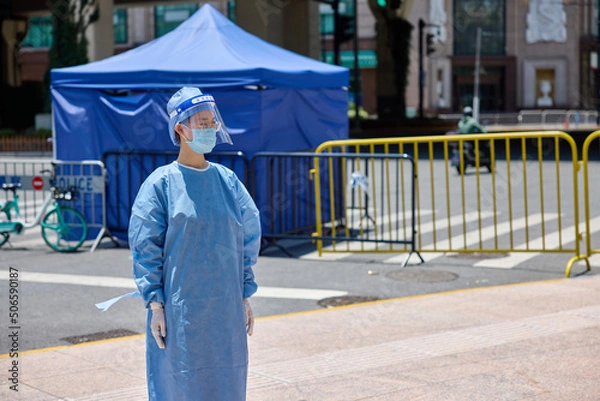 Fototapeta Medical worker in protective suits and surgical face masks on the street. City blockade.
