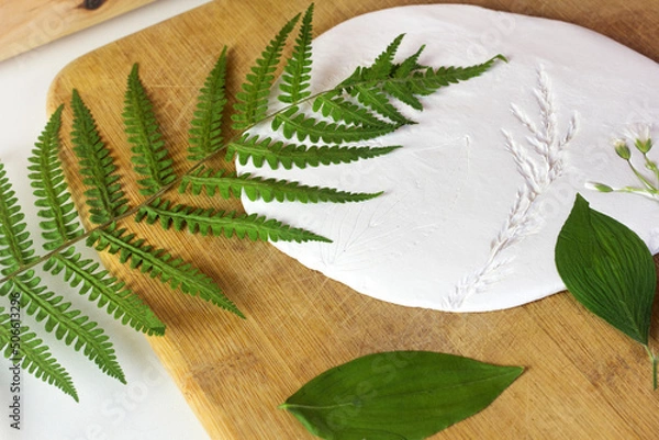 Fototapeta Ceramic class Dried leaves on the white clay close up. Creative process. Pottery workshop studio