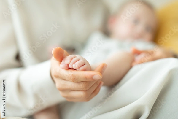 Fototapeta 赤ちゃんの足を握る母親の手元