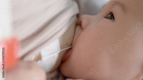 Obraz Mother breastfeeding baby with SNS system. Close up view