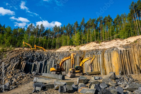 Fototapeta Basalt mining. Yellow excavators in a basalt quarry. Basaltic and sandstone rocks.