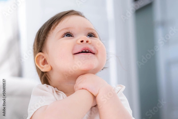 Fototapeta Excited cute little baby girl thinking of something dreaming or having a good idea, smiling and looking up, imagination 