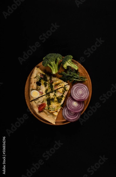 Obraz Isolated wooden board with pizza, broccoli and onions.  View from above. Pizza on black background. 