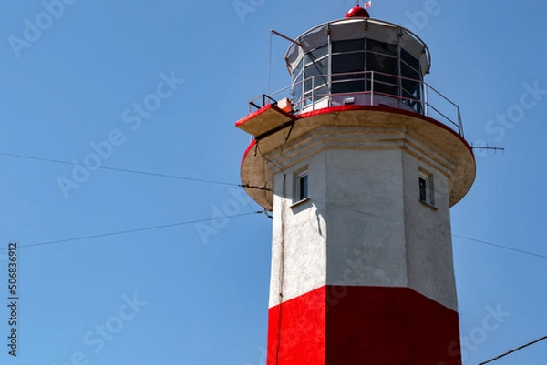 Obraz Lighthouse on the sea. Red-white lighthouse on the island. Lighthouse against the sky. Beautiful building by the sea. Ukrainian lighthouse.