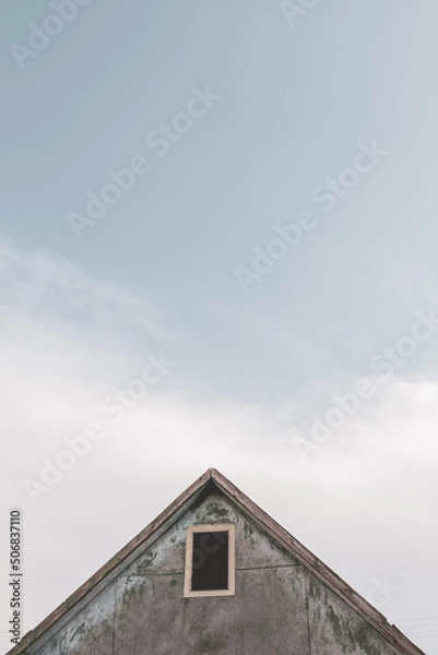 Obraz Old house on the background of a beautiful sky. Clouds on the blue sky. Bright sunny day in the village.