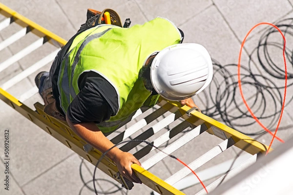 Obraz electrician worker on staircase installing optical fiber cable for internet and telephone lines in city street