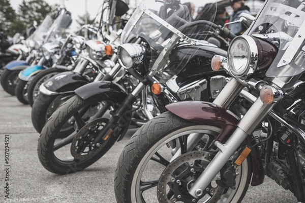 Fototapeta Motorcycles parked in a line in a motorcycle parking lot. Close-up of the front wheel of a motorcycle