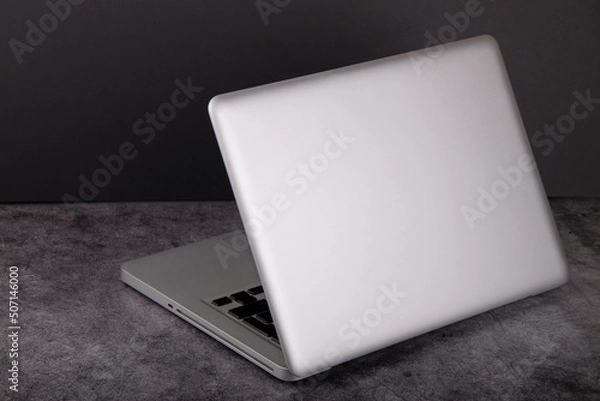 Fototapeta The laptop is silver on a dark background