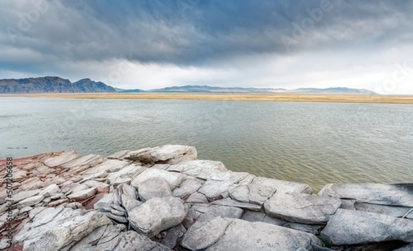 Obraz The shore of the Krasnoyarsk reservoir, gray sandstone and stones with slabs on the shore, rainy sky over Mount Tepsey Tepsei